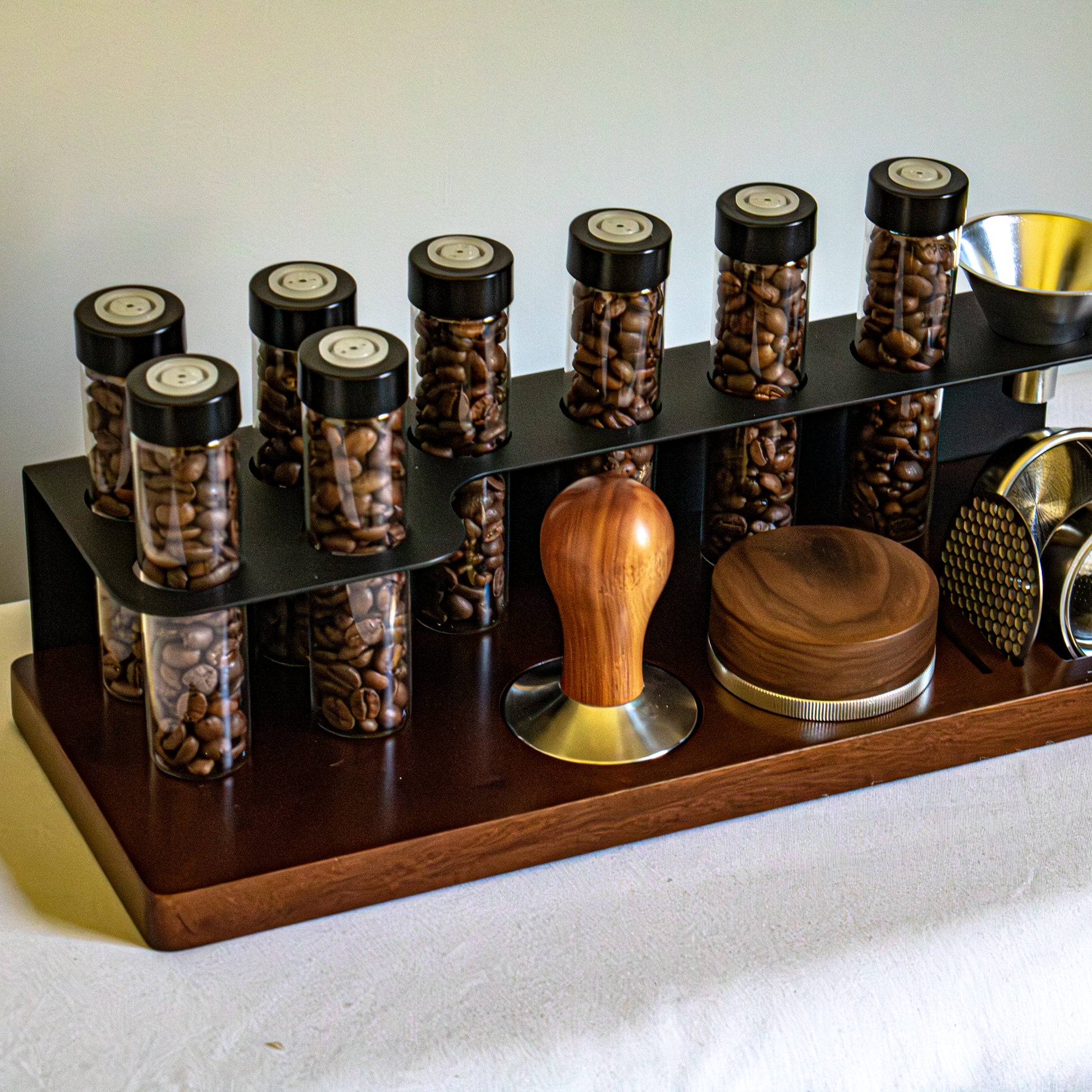 Set of coffee beans in jars with a wooden and metal tamp on a white surface