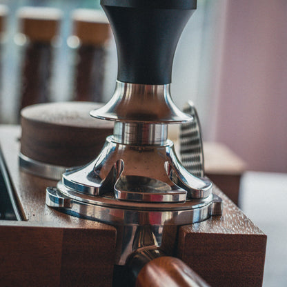 Black espresso tamper on tamping station
