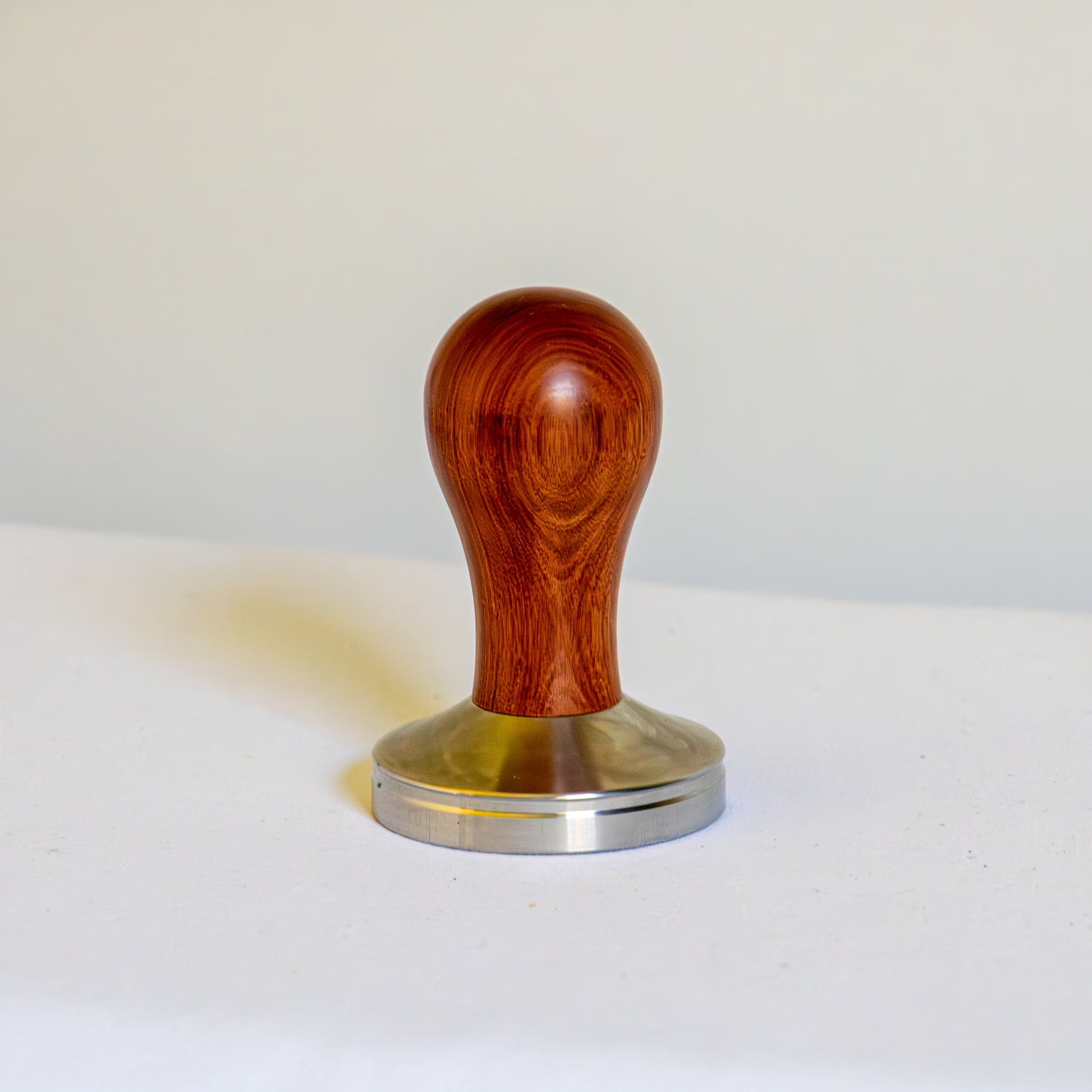Wooden tamper with metal base on a white background